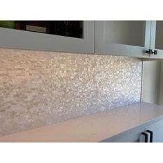 a kitchen counter top with white cabinets and tile backsplash in the backround