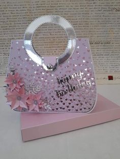 a pink handbag is sitting on top of a card holder that says happy birthday