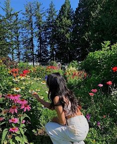 a woman kneeling down in a field of flowers