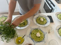 a person preparing food on top of a white kitchen counter with blue and white plates