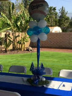 a table set up with balloons and baseballs on it in the middle of a yard