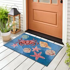 a blue door mat with shells and starfishs on it next to a potted plant