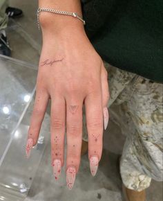 a woman's hand with pink and white nail polishes on her left thumb