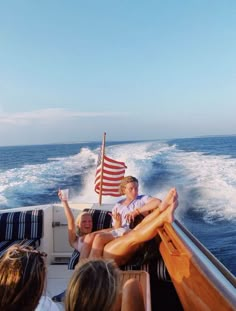 some people are sitting on a boat in the water and one is holding an american flag