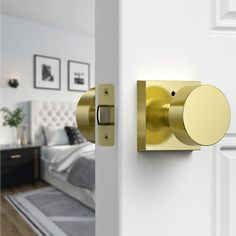 an open door with a gold knob on the side and a white bed in the background