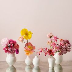 three white vases filled with different colored flowers