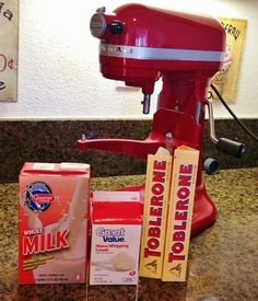 a red blender sitting on top of a counter next to two boxes of milk