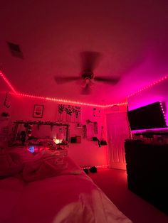 a bedroom with pink lights and pictures on the wall