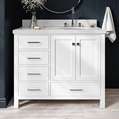 a white bathroom vanity with two sinks and a round mirror on the wall above it