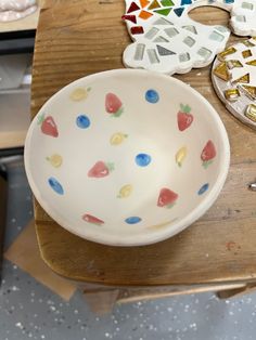 a white bowl sitting on top of a wooden table next to other crafting supplies