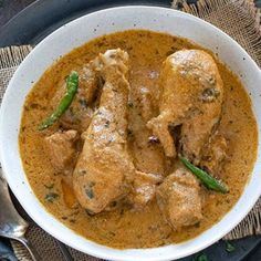 a white bowl filled with chicken and green beans on top of a cloth covered table