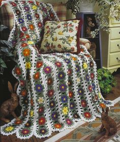 a crocheted blanket with flowers on it and a bunny sitting next to it