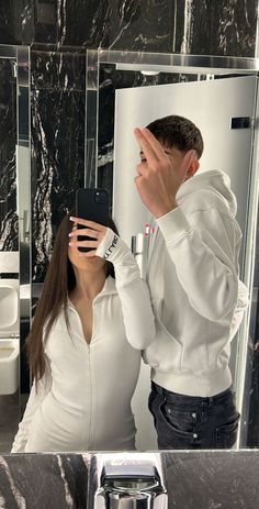 a man and woman standing in front of a bathroom mirror