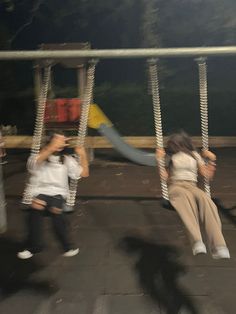 two children are playing on swings at night