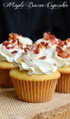 three cupcakes with white frosting and bacon on top sitting on a table