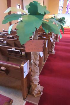 a small palm tree in the middle of a church pews with paper cutouts on it