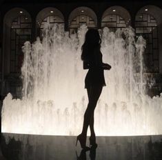 a woman standing in front of a water fountain