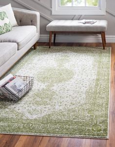 a living room with a white couch and green area rug on top of wooden flooring