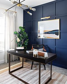 a room with blue walls and a black desk in the middle, along with a rug on the floor