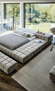 a large bed sitting in the middle of a living room next to a glass wall