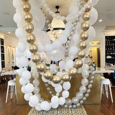 a table topped with lots of white and gold balloons on top of a wooden floor