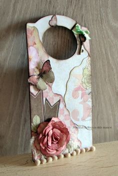 an altered door hanger with a pink flower and butterfly decoration on it's side