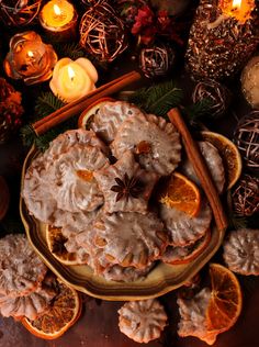 a plate with oranges and cinnamon cookies on it next to candles, decorations and other items