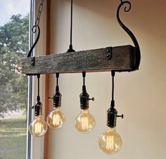 three light bulbs hanging from a wooden beam in a room with windows and trees outside