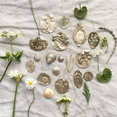 a bunch of different types of coins and flowers on a white cloth with green leaves