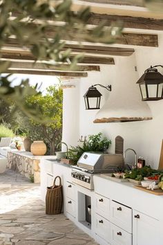 an outdoor kitchen with lots of counter space and hanging lights on the wall above it