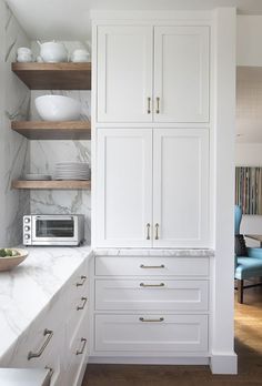 a kitchen with marble counter tops and white cabinets, along with open shelving units