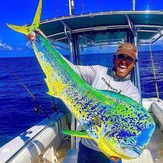 a man on a boat holding a big fish in his hands and smiling at the camera