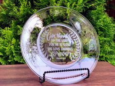 a glass plate with a quote on it sitting on a table next to some plants