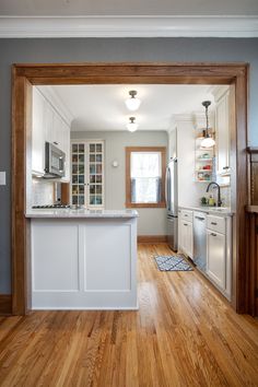 an open kitchen with white cabinets and wood floors