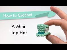 a hand holding a tiny crochet top hat with the words how to crochet on it