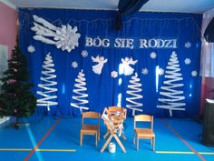 a stage set up with chairs and christmas decorations on the wall, decorated in white snowflakes