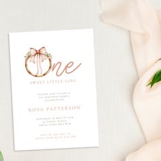 a white card with a pink bow and the word one is on top of it