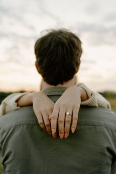 a person with their hand on the back of his shoulder, looking at the sky