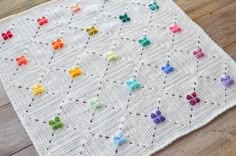 a white crocheted blanket with multicolored flowers on it