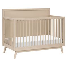 a baby crib that is white and has a mattress on the bottom half of it