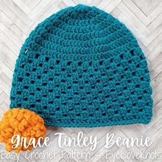 a crocheted beanie with an orange pom - pom on it