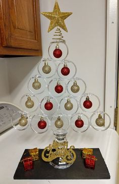 a christmas tree made out of wine glasses with gold and red ornaments on top, sitting on a counter