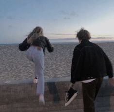 two people are walking on the beach at sunset with one person carrying his skateboard