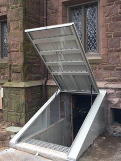 an open metal door on the side of a brick building in front of a window