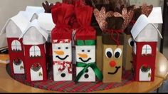 christmas presents sitting on top of a table next to small houses and snowmen made out of paper bags