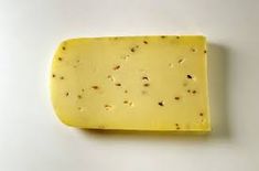 a piece of cheese on a white surface with tiny speckles around the edges