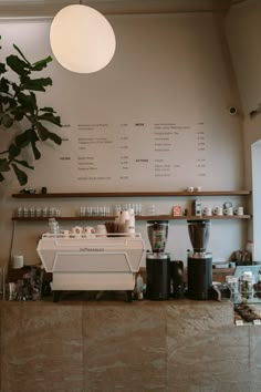 a coffee shop with lots of cups on the counter and plants growing in the corner