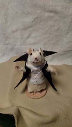 a toy mouse dressed up in a suit and tie on top of a cloth covered surface