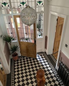 a foyer with black and white checkered flooring and chandelier above the door