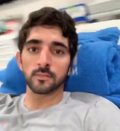 a man with a mustache is sitting in a hospital bed and looking at the camera